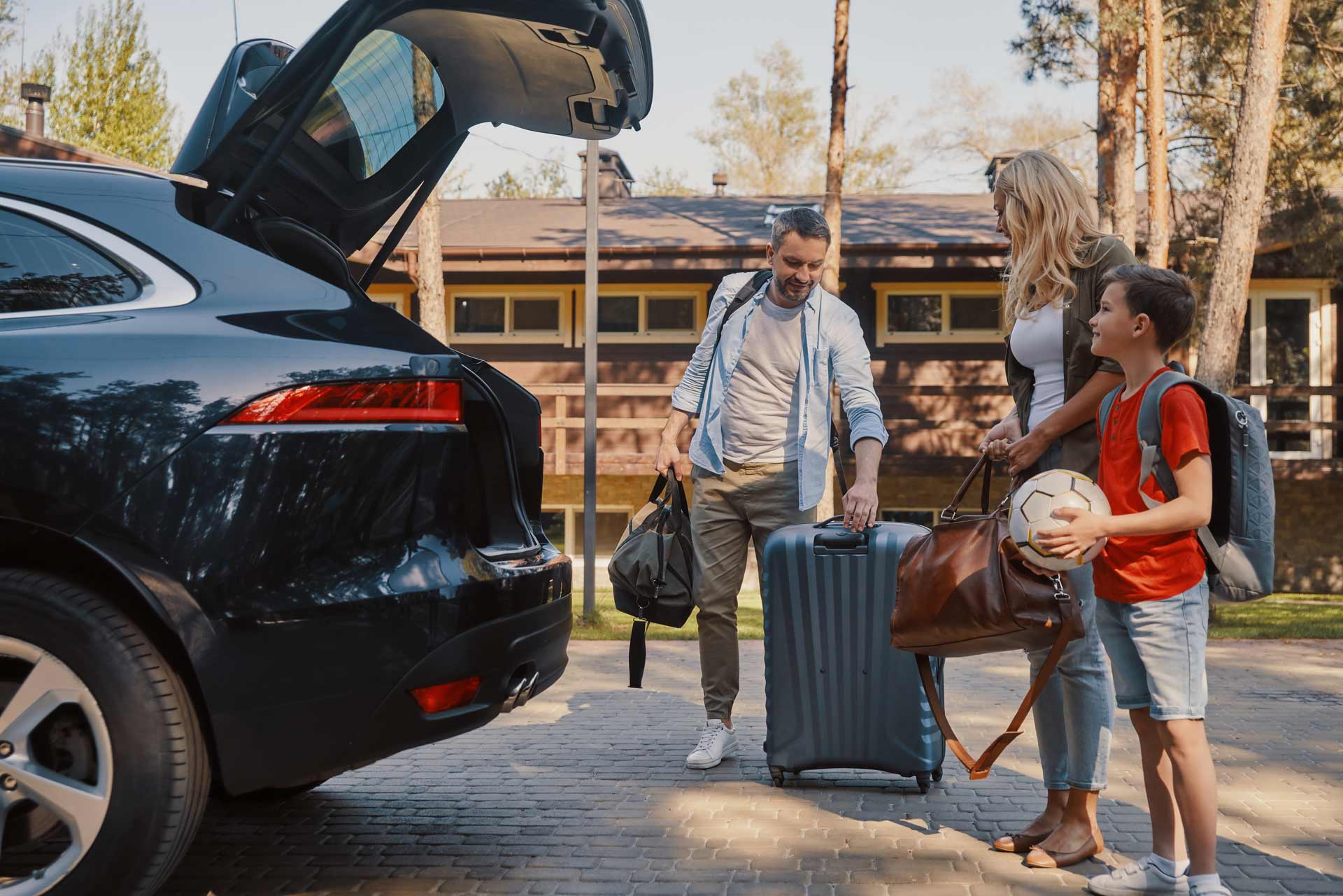 Young family loading luggage into car.